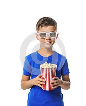 Cute little boy with cup of popcorn wearing 3D cinema glasses on white background