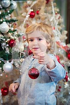 Cute little boy decorating Christmas tree.