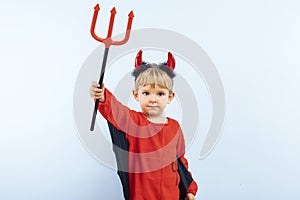 Cute little boy in devil halloween costume with horns and trident