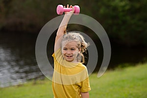 Cute little boy doing exercises with dumbbells. Portrait of sporty child with dumbbells. Happy child boy exercising
