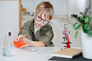 Cute little boy doing science project, filling glass chemical dish from a beaker