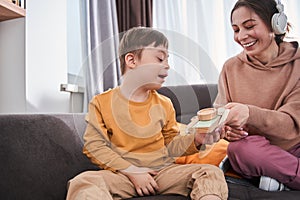 Cute little boy with Down syndrome playing with his mother at the sofa