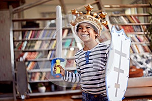 A cute little boy dressed as knight is posing for a photo while playing at home. Family, home, playtime photo