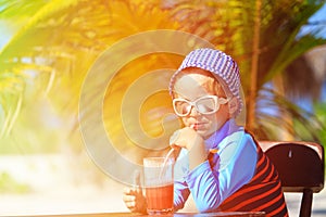 Cute little boy drinking juice on tropical beach