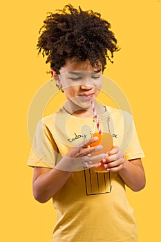 Cute little boy drinking orange juice with a straw