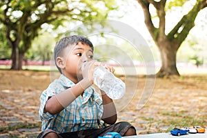 Cute little boy drinking water in the green park,focus hand