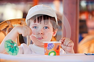 Cute little boy eating ice cream at indoor cafe