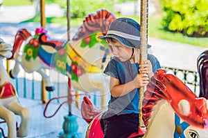 Cute little boy enjoying in funfair and riding on colorful carousel house photo