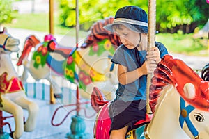Cute little boy enjoying in funfair and riding on colorful carousel house photo