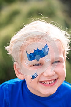 Cute little boy with face paint with batman pattern