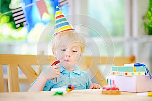 Cute little boy having fun and celebrate birthday party with colorful decoration and cake