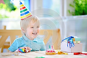 Cute little boy having fun and celebrate birthday party with colorful decoration and cake