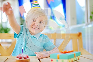 Cute little boy having fun and celebrate birthday party with colorful decoration and cake