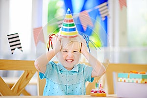 Cute little boy having fun and celebrate birthday party with colorful decoration and cake