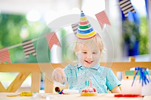 Cute little boy having fun and celebrate birthday party with colorful decoration and cake