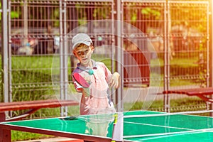 Cute little boy having fun playing table tennis in park sport ground