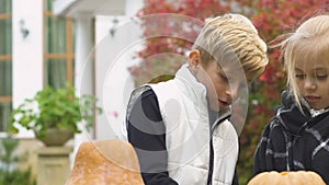 Cute little boy helping his friend to carve pumpkin lantern for Halloween party