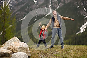 Cute little boy and his father walks in Swiss national Park on spring. Hiking with little kids. Dangerous situation: standing on