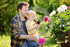 Cute little boy with his father working together with secateur in domestic garden