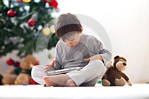 Cute little boy and his monkey toy, playing on tablet