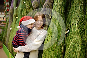 Cute little boy with his mother chooses christmas tree on market. Family Christmas shopping