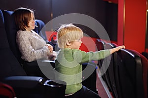 Cute little boy with his mother watching cartoon movie in the cinema