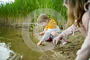 Cute little boy and his sister playing by a lake or river on hot summer day. Adorable child having fun outdoors during summer