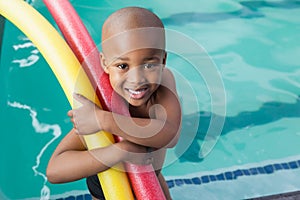 Cute little boy holding foam rollers by the pool