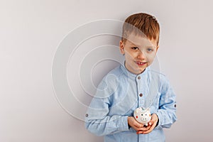 Cute little boy holding a piggy bank or money box.