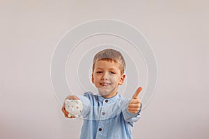 Cute little boy holding a piggy bank or money box.