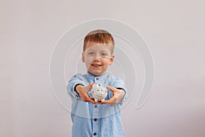 Cute little boy holding a piggy bank or money box