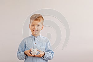 Cute little boy holding a piggy bank or money box. Concept child and money