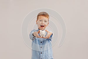 Cute little boy holding a piggy bank or money box. Concept child and money