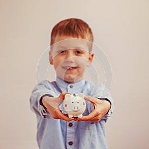 Cute little boy holding a piggy bank, soft focus on money box