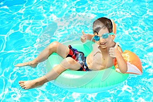 Cute little boy with inflatable ring resting in swimming pool