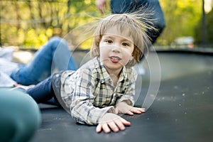 Cute little boy jumping on a trampoline in a backyard on warm and sunny summer day. Sports and exercises for children