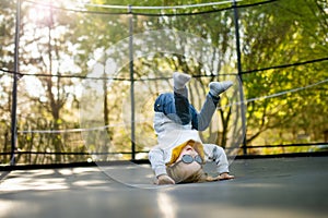 Cute little boy jumping on a trampoline in a backyard on warm and sunny summer day. Sports and exercises for children