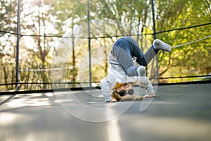 Cute little boy jumping on a trampoline in a backyard on warm and sunny summer day. Sports and exercises for children