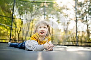 Cute little boy jumping on a trampoline in a backyard on warm and sunny summer day. Sports and exercises for children