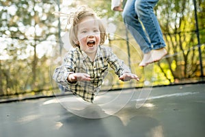 Cute little boy jumping on a trampoline in a backyard on warm and sunny summer day. Sports and exercises for children