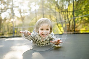 Cute little boy jumping on a trampoline in a backyard on warm and sunny summer day. Sports and exercises for children