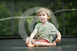 Cute little boy jumping on a trampoline in a backyard on warm and sunny summer day. Sports and exercises for children. Summer