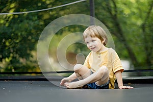 Cute little boy jumping on a trampoline in a backyard on warm and sunny summer day. Sports and exercises for children. Summer