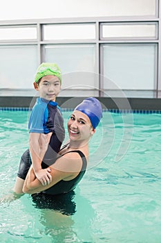 Cute little boy learning to swim with coach