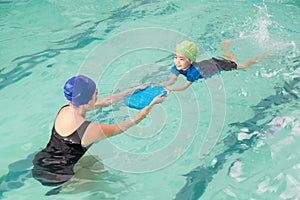 Cute little boy learning to swim with coach