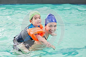 Cute little boy learning to swim with coach