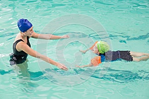 Cute little boy learning to swim with coach