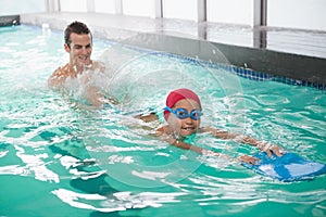 Cute little boy learning to swim with coach