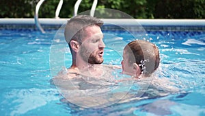 Cute little boy learning to swim with parents in pool