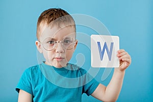 Cute little boy with letter on blue background. Child learning a letters. Alphabet